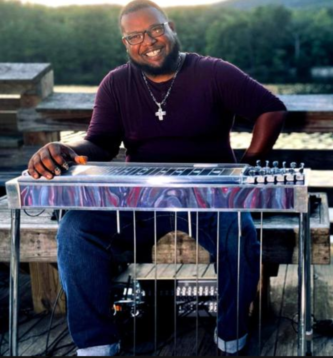An African American man sitting at a steel guitar